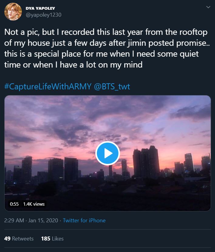 Tweet from an ARMY participating in the Bonus Mission Capture Life With ARMY. Tweet shows a frame from a video they recorded from the rooftop of their house at sunset. In the distance you can see several tall apartment or commercial towers. The sky is a gradient of purple, pink, yellow, and orange.