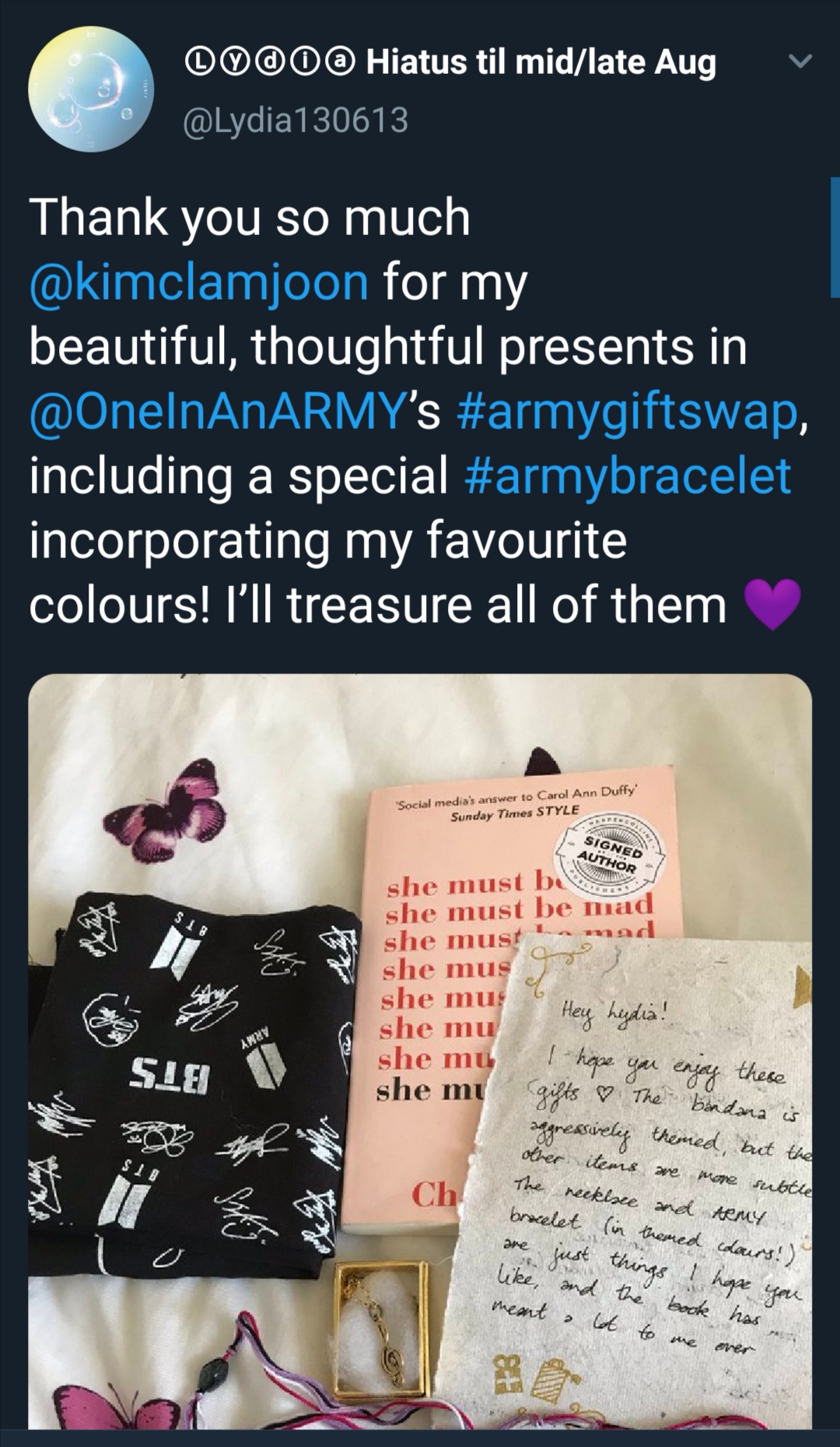 Tweet showing what an ARMY named Lydia received through the ARMY Gift Swap. The photo shows a book, letter, piece of jewelry, and a t-shirt