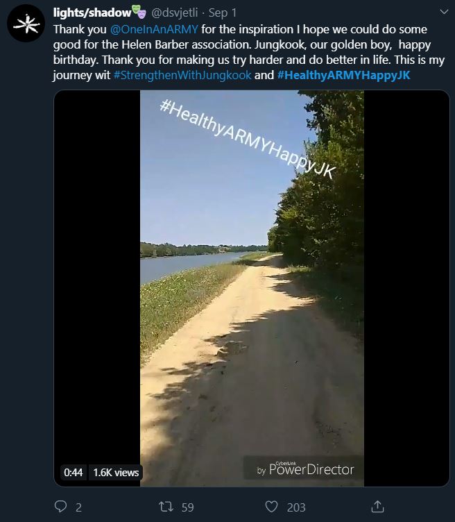 Tweet showing an ARMY participating in the bonus mission Healthy ARMY Happy Jungkook. The tweet shows a still frame from a video of the ARMY walking or biking along a dirt road with a body of water to their left.